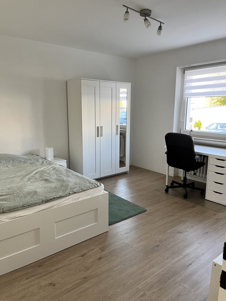 Schlafzimmer im möblierten Apartment Sindelfingen mit Doppelbett und Kleiderschrank, Smart TV und Schreibtisch